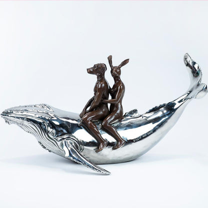 Bronze and stainless steel Sculpture of a dog man and rabbit woman riding on a whale. Side view.